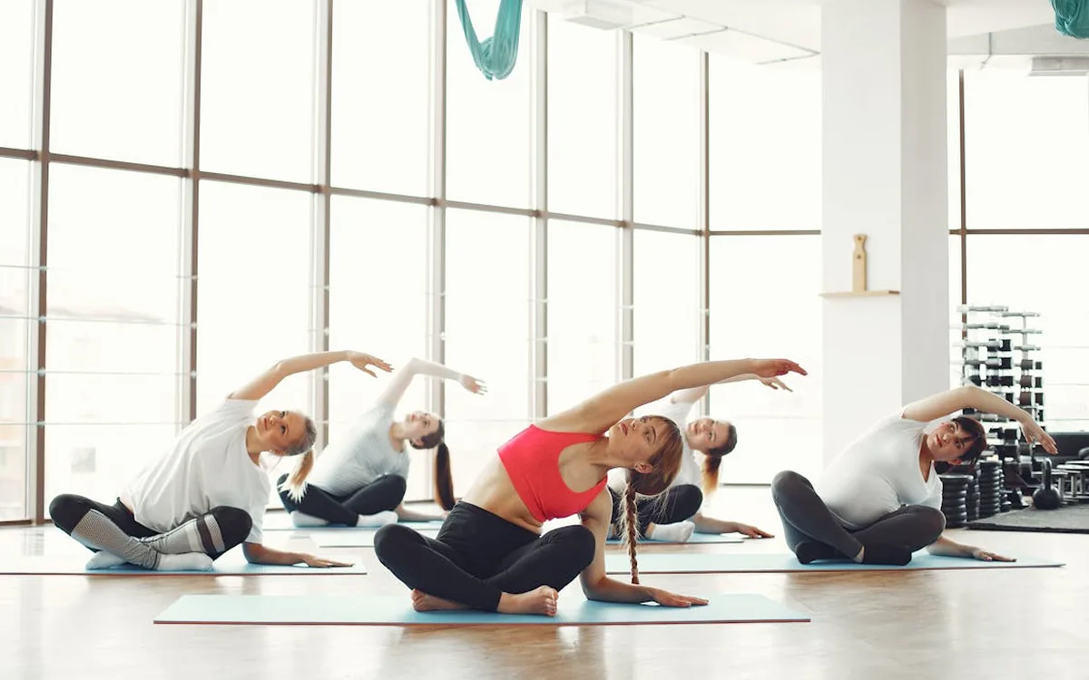 Turma de Pilates mat com mulheres em exercício de alongamento lateral — Studio Livel